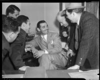 Film actor Clark Gable sitting with a group of admirers, Los Angeles, 1937