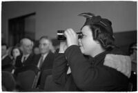 Female spectator uses binoculars to view court proceedings during the trial of Police Captain Earle E. Kynette, Los Angeles, 1938