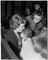 Miss Leo C. Moore sitting in a crowd holding her young child, Los Angeles