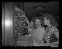 Three women tourists looking at post cards in Los Angeles' Union Station novelty shop, circa 1947