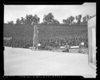 Actress Carole Landis performing before crowd of Army soldiers at Fort Hunter Liggett, Calif. during 1941 Hollywood stars show