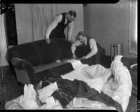 Detective Lieutenant Miles Ledbetter and Ray Pinker search under sofa cushions for evidence, Los Angeles, 1935