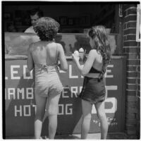 Two young girls buying snow cones on the boardwalk on Labor Day, Los Angeles, September 3, 1945