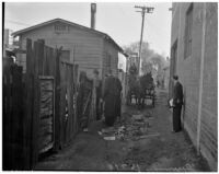 Four men stand aside as a horse-drawn wagon drives through an alley in the slums, Los Angeles, 1925-1945