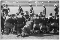 Loyola Lions in a huddle with their coaches on the Coliseum field, Los Angeles, 1937