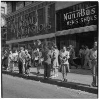 Woman talking to truant teenagers in the crowd in downtown Los Angeles, March 1946