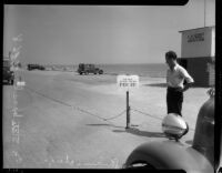 Unidentified man stands next to parking charge sign at state beach, Los Angeles, 1930s