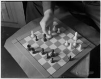 Top view of a chess board and player's hand moving the white queen, Los Angeles