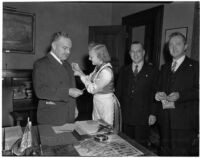 Dressed in traditional Scandinavian clothing, 14-year-old Anita Roos sells Mayor Bowron the first ticket to the Finnish Relief bazaar, Los Angeles, 1940