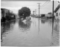 Automobile drives through a flooded street caused by heavy rainstorms, January 1940