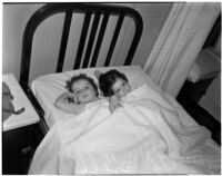 Young girls Barbara and Rosalie Bell laying next to each other in a twin-sized bed, Los Angeles