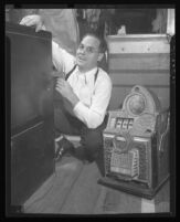 Rev. Wesley Anderson poses in front of a safe and next to a slot machine, 1945