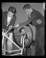 John Maggi, John Trapp and John Nicholson wearing YMCA sweaters, working on bicycle in Eagle Rock, Calif., 1953