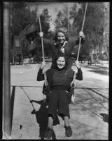 Two unidentifed women play on a swing set during the annual Iowa Picnic, Los Angeles, 1930s