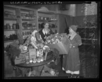 Aimee Semple McPherson and Mrs. M. B. Godbey in a pantry preparing Christmas food baskets, circa 1935