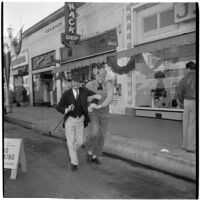 Fred Beck and L.B. Roquett walk arm-in-arm down the street during Anaheim's annual Halloween festival, Anaheim, October 31, 1946