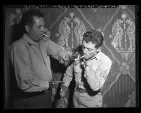 Two veterans with prosthetic hands lighting up cigarettes during 1946 National Employ the Physically Handicapped Campaign Committee meeting