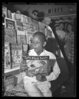 African American boy reading a Little Black Sambo book in a Los Angeles Drugstore, circa 1947