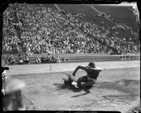 Jesse Owens lands a jump during a track meet, Los Angeles, 1930s