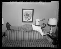 Hank Ketcham, "Dennis the Menace" cartoonist, laying on back of couch, Calif., circa 1953