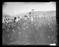 Jubilant group of military men holding up shovels and rakes during service as wildfire fighters in Orange County, Calif., 1948