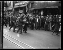 Police dragging off man as crowd watches during unemployment demonstration led by communists, dubbed "Red Riot" in Los Angeles, Calif., 1930