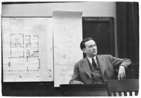 Murder suspect Robert S. James sitting on the witness stand with a plan of his house behind him, Los Angeles, 1936