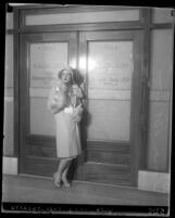 Motion picture actress Clara Bow posing in front of Los Angeles Grand Jury room doors, 1930