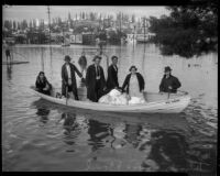 Unidentified men and women carry belongings and pets across flood waters, Long Beach, circa 1930s