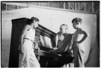 Boys gathered around piano and pianist, taking part in a free summer camp organized by Los Angeles Sheriff Eugene Biscailuz. Circa July 1937