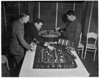 Albert Smith, Jerry Ramlow, and Barney Bernard with gambling equipment confiscated during a police raid on 1019 N. Doheny Rd., Los Angeles, January 1938
