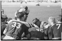 Loyola Lions in a huddle with their coaches on the Coliseum field, Los Angeles, 1937