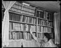 Man takes a book from a bookshelf at the Unemployed Citizens' League of Santa Monica, 1930s