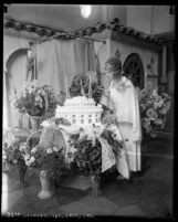 Aimee Semple McPherson surrounded by flowers, cutting into Angelus Temple cake