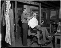 Man gets a haircut from a smiling barber at a cooperative in Los Angeles, 1930s