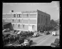 Long line of people standing outside Los Angeles Department of Motor Vehicles building waiting for 1940 automobile licenses, 1940