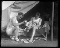 Two runners caring for their feet during a break in C. C. Pyle's Route 66 cross country footrace called the "Bunion Derby," 1928