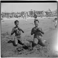 Two boys cover themselves with wet sand at the beach on Labor Day, Los Angeles, September 3, 1945