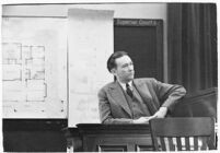 Murder suspect Robert S. James sitting on the witness stand with a plan of his house behind him, Los Angeles, 1936