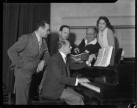 Group of people gather around a piano at a La Boheme performance at the Shrine Auditorium, Los Angeles, 1935