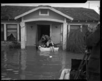 Unidentified man and woman in a boat outside a flooded home, Long Beach, circa 1930s