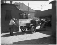 Men load a large crate into an automobile at a cooperative in Los Angeles, 1930s
