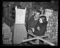 Couple in grocery store reading food stamps poster in Los Angeles, circa 1940