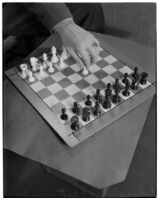 Top view of a chess board and a player's hand making the first move of the game, Los Angeles