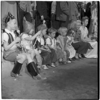 Children sitting on the sidewalk and enjoying the post-war Labor Day parade, Los Angeles, 1946