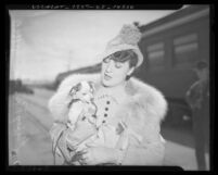 Half length portrait of burlesque entertainer Gypsy Rose Lee carrying dog at train station, circa 1937