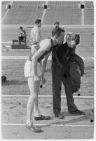 USC track athlete speaking to a coach on the Coliseum field, Los Angeles, 1937
