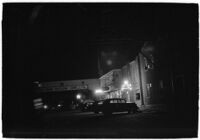 Row of businesses including a liquor store, a cafe, the LA I.D.A. and the Sea Pride Packing Company at night, Los Angeles, 1930s