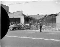 Crowd gathered to see the wreckage after an automobile swerved off the road and crashed into the front of a building, Los Angeles, 1940s