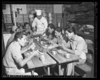 Cook serving food to eight jail trustees in the Los Angeles County Jail kitchen, circa 1943